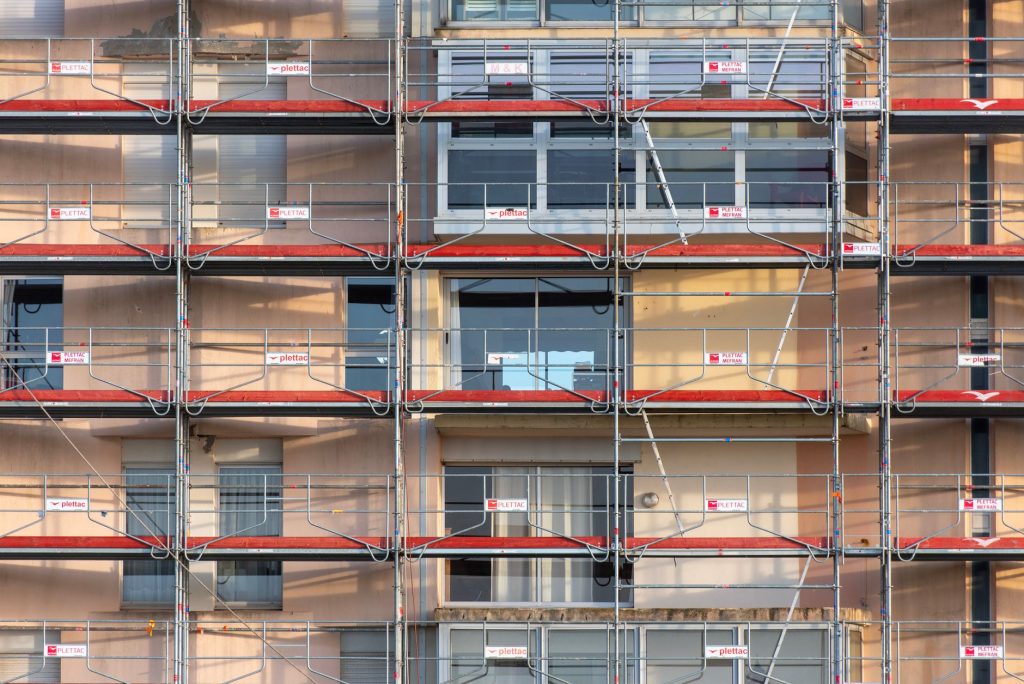 Hausfassade mit mehrlagigem Baugerüst und Netzverkleidung über die volle Höhe
