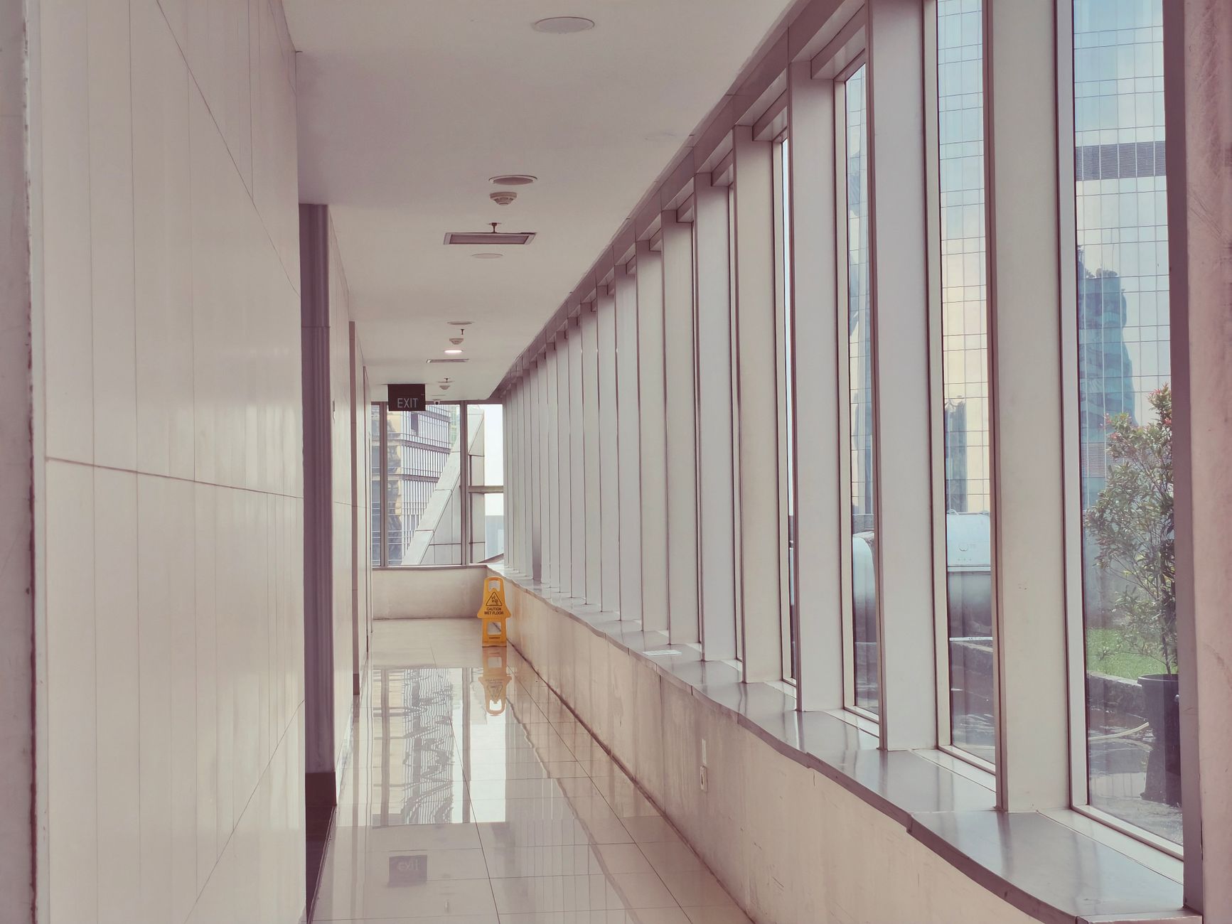 Heller Flur in einem Bürogebäude mit frisch gewischtem, spiegelndem Boden und Fensterfront