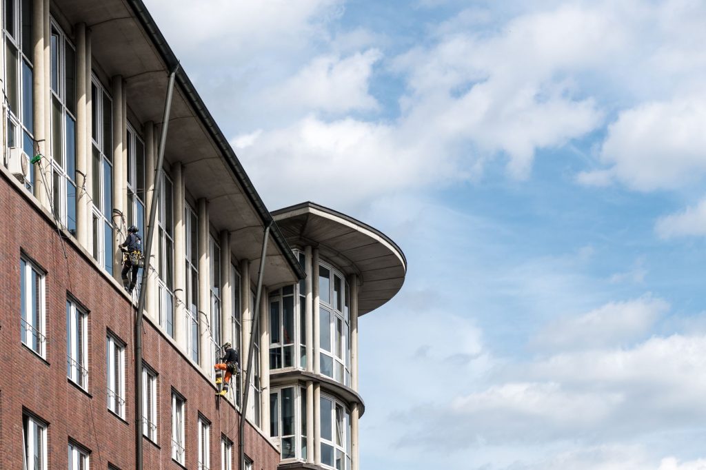Zwei Fensterreiniger arbeiten per Seilzugang an der Fensterfront eines Bürogebäudes